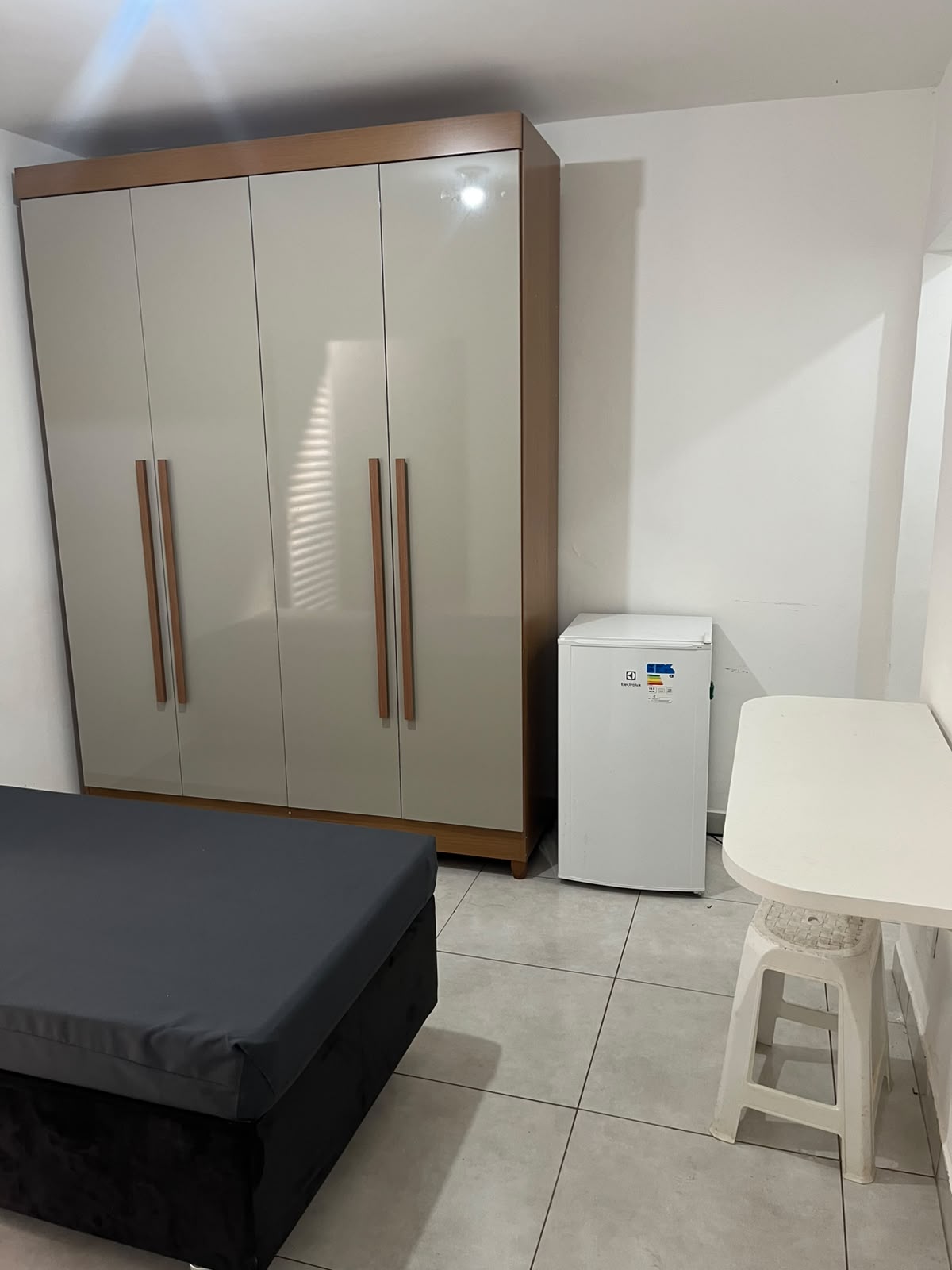 Quarto com guarda-roupa, frigobar e mesa